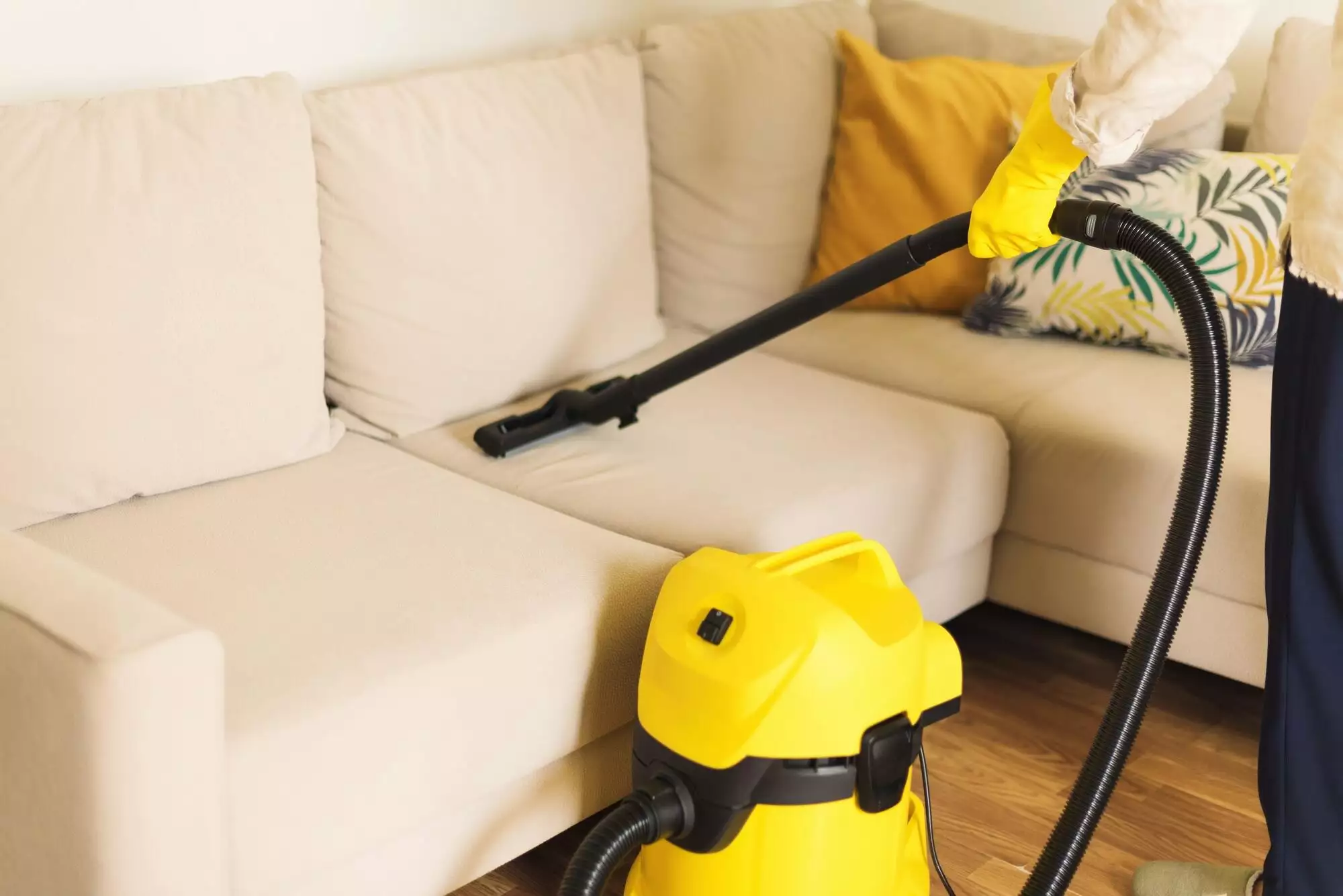 Woman cleaning sofa with yellow vacuum cleaner. Copy space. Clean concept
