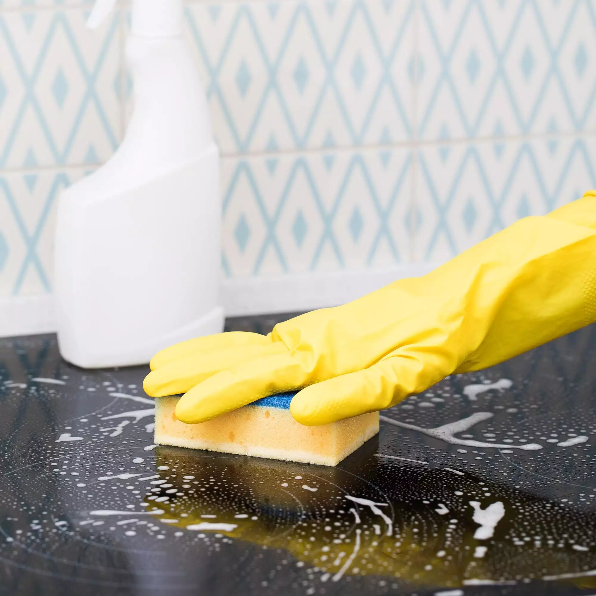 Yellow sponge on the stove in the foam. General cleaning concept.